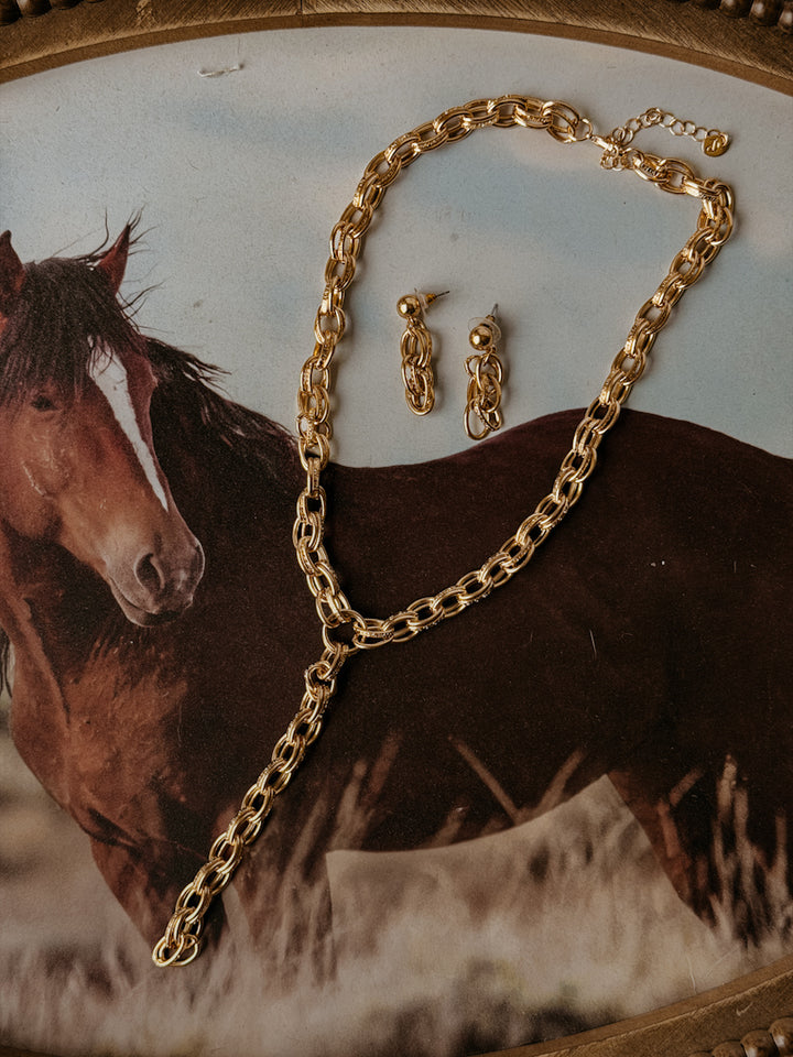 Gold necklace and earrings on a background with a horse illustration