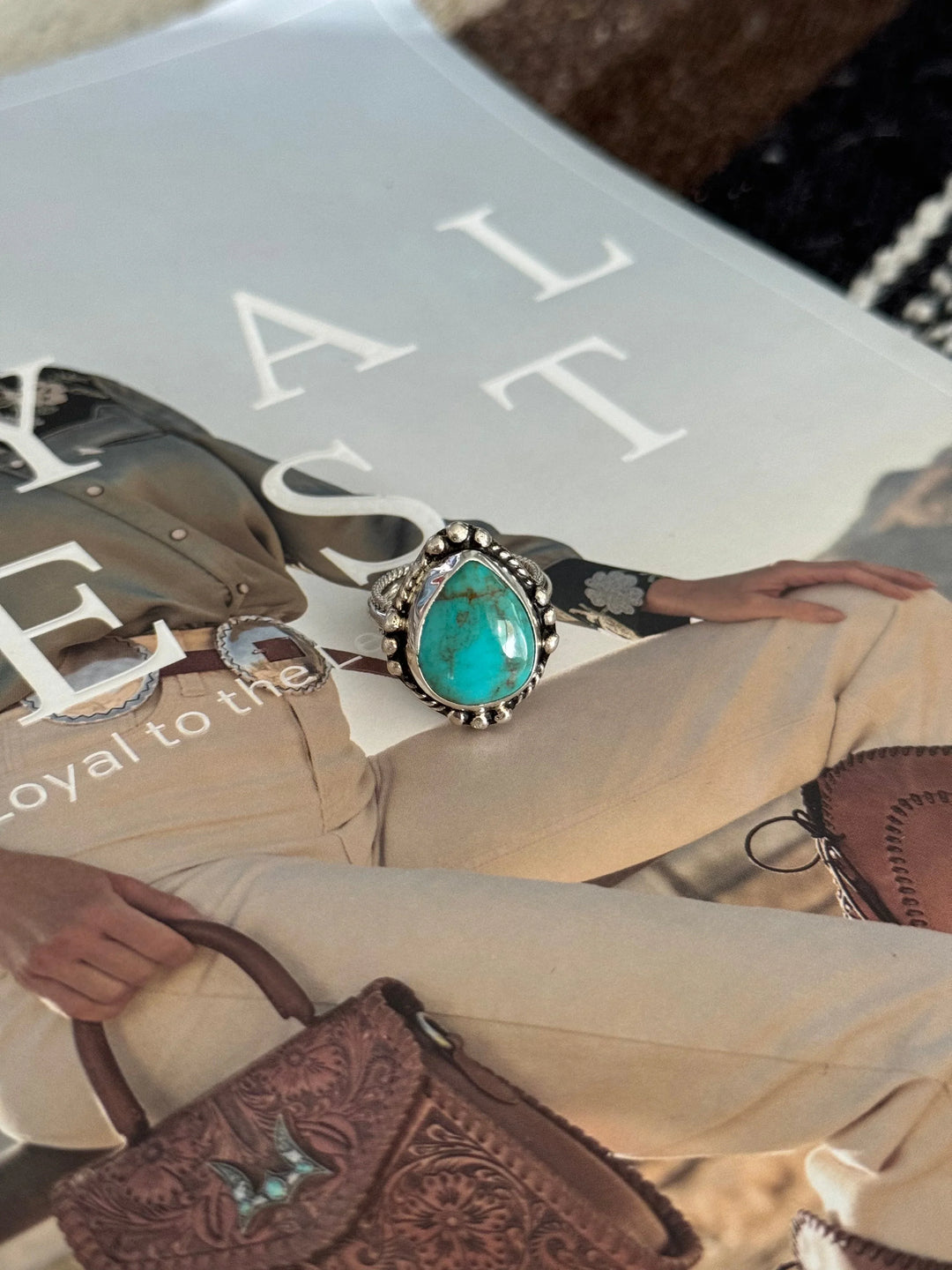 Turquoise western boho ring with silver detailing on magazine featuring western outfit