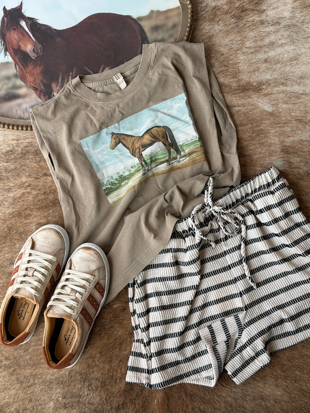 T-shirt with horse graphic, shorts, and sneakers on a wooden surface