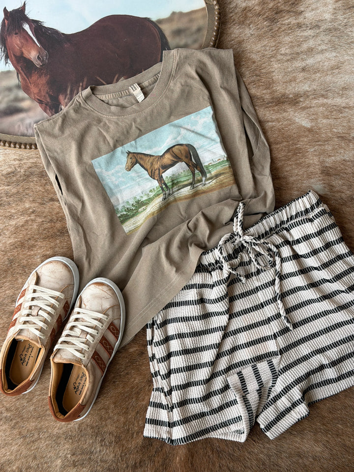 T-shirt with horse graphic, shorts, and sneakers on a wooden surface