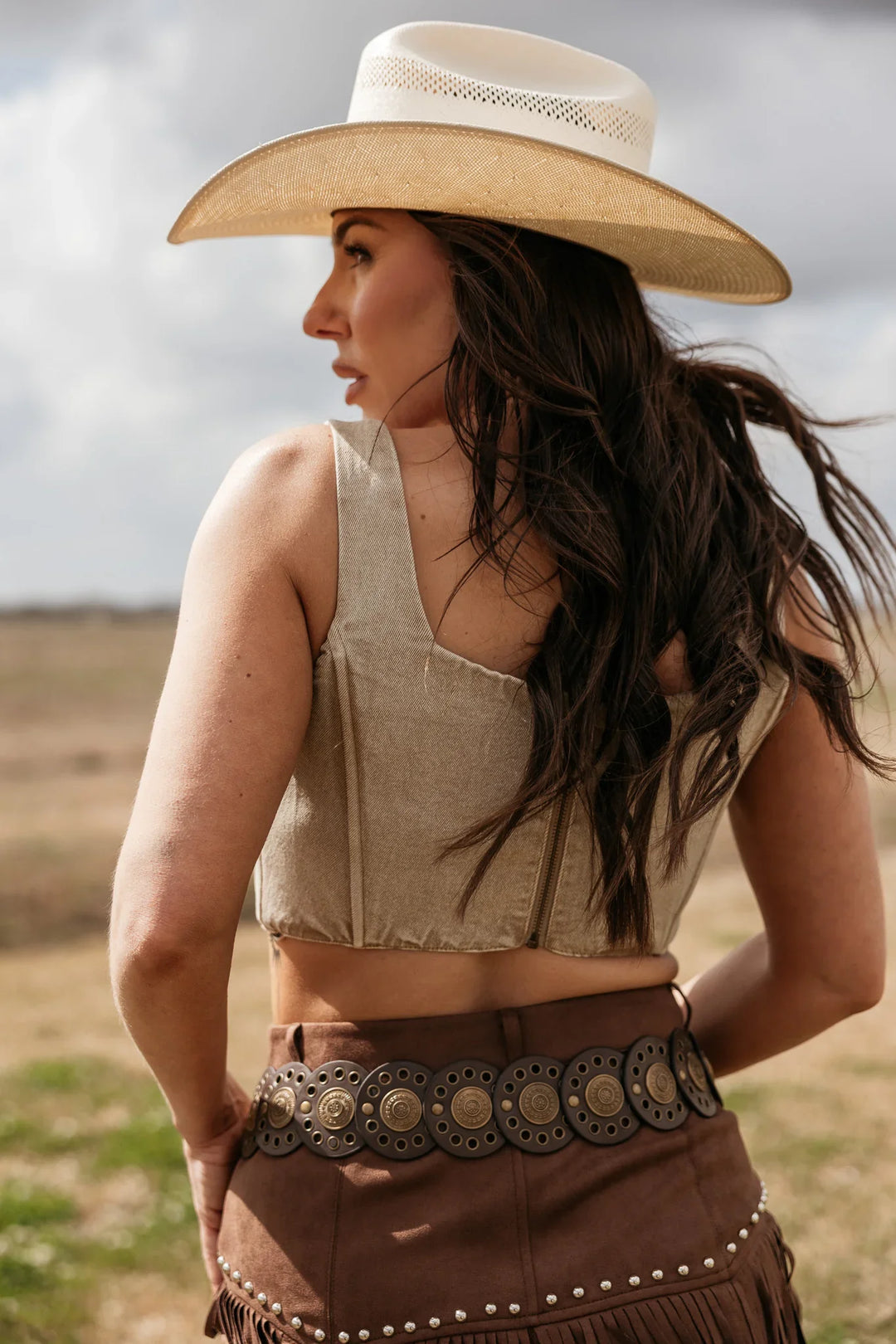 Woman wearing a cowboy hat and a patterned belt in an outdoor setting