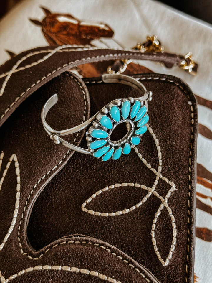 Turquoise western cuff bracelet on brown embroidered suede with horse print background