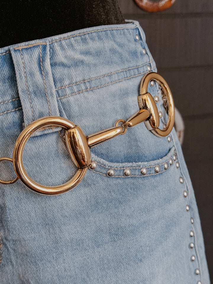 Gold equestrian bit accessory on a denim background