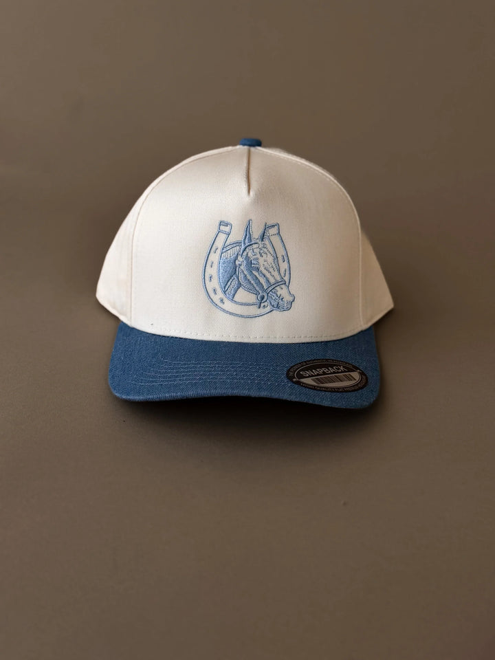 Western snapback hat with blue horse and horseshoe embroidery, cream crown, blue brim.