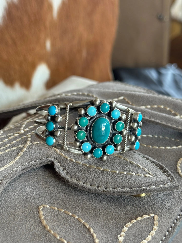 Western turquoise silver cuff bracelet with floral design on embroidered suede background
