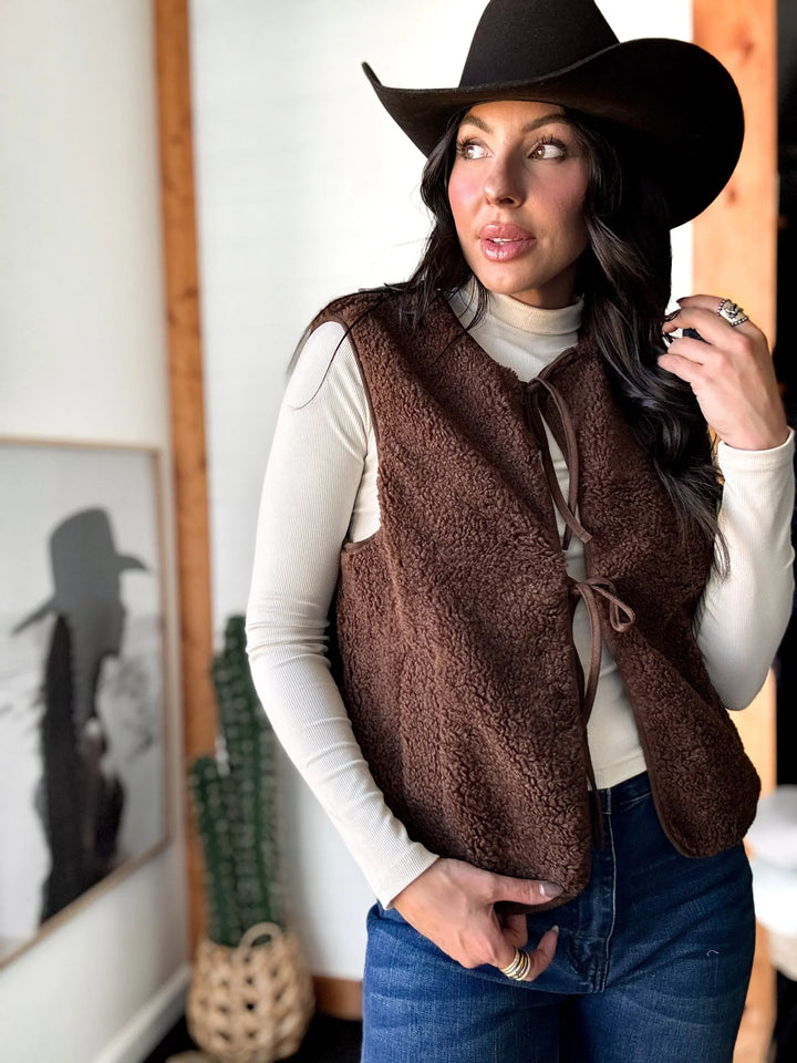 Woman wearing a brown vest and hat indoors