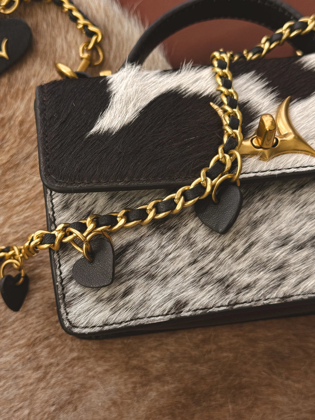Handbag with gold chain and cowhide texture on a fur surface
