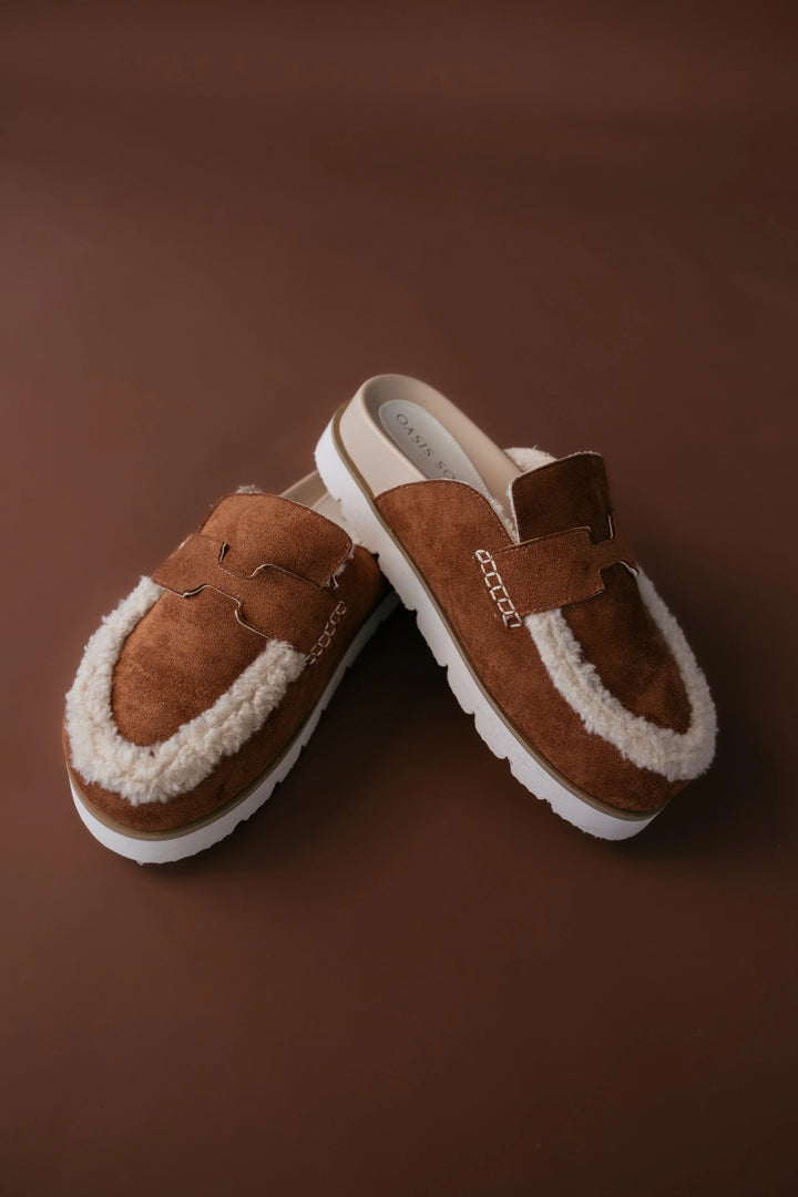 Pair of brown slippers with white soles on a brown background