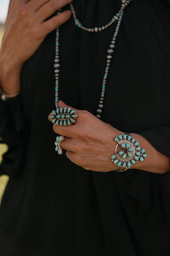 Turquoise jewelry set including necklace, bracelet, and ring on a black background