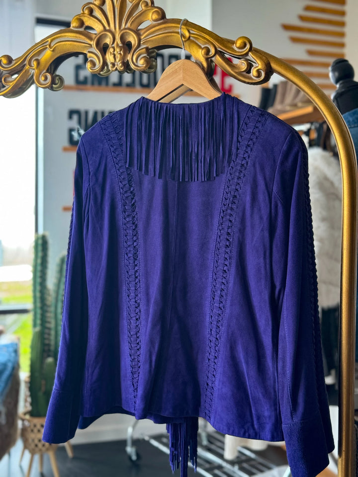 Purple suede western fringe jacket with braided details, hanging on gold rack indoors