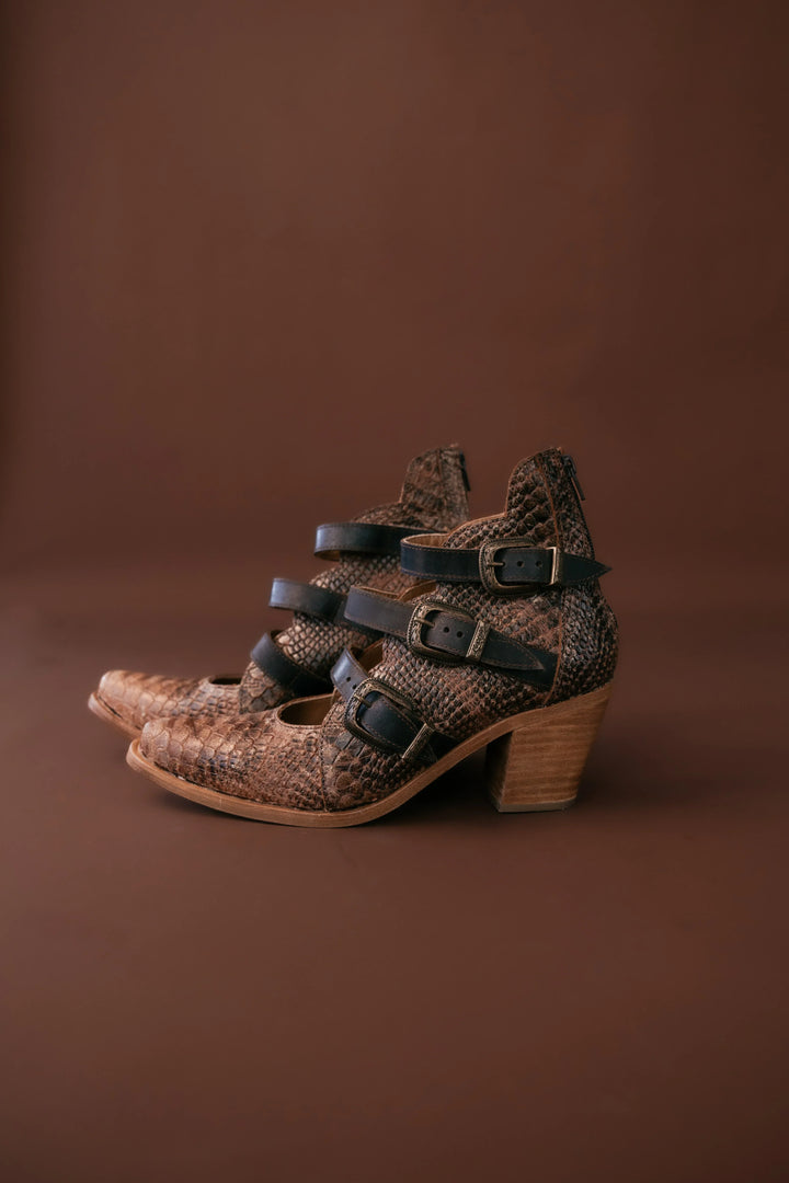 Pair of brown patterned shoes with wooden soles on a brown background