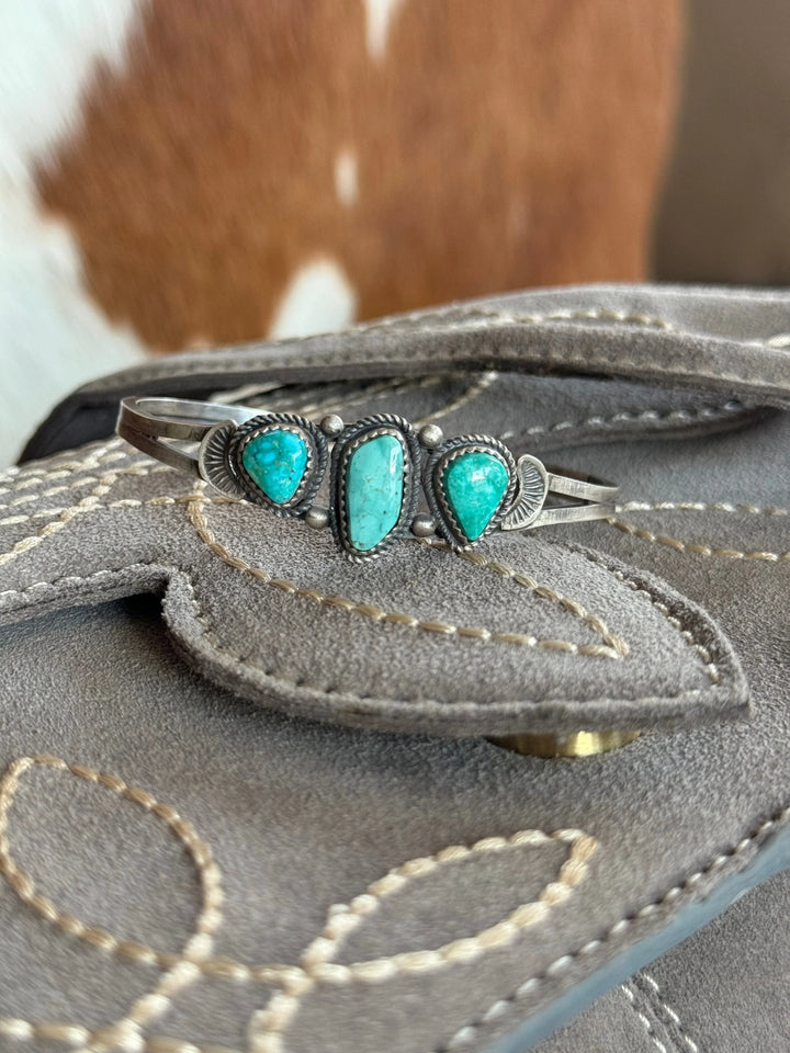 Turquoise silver western cuff bracelet on stitched gray suede with cowhide background