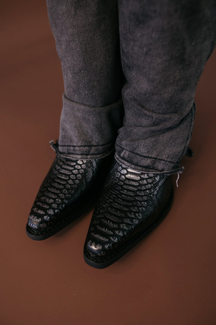 Black snakeskin western cowboy boots with pointed toes and distressed black jeans