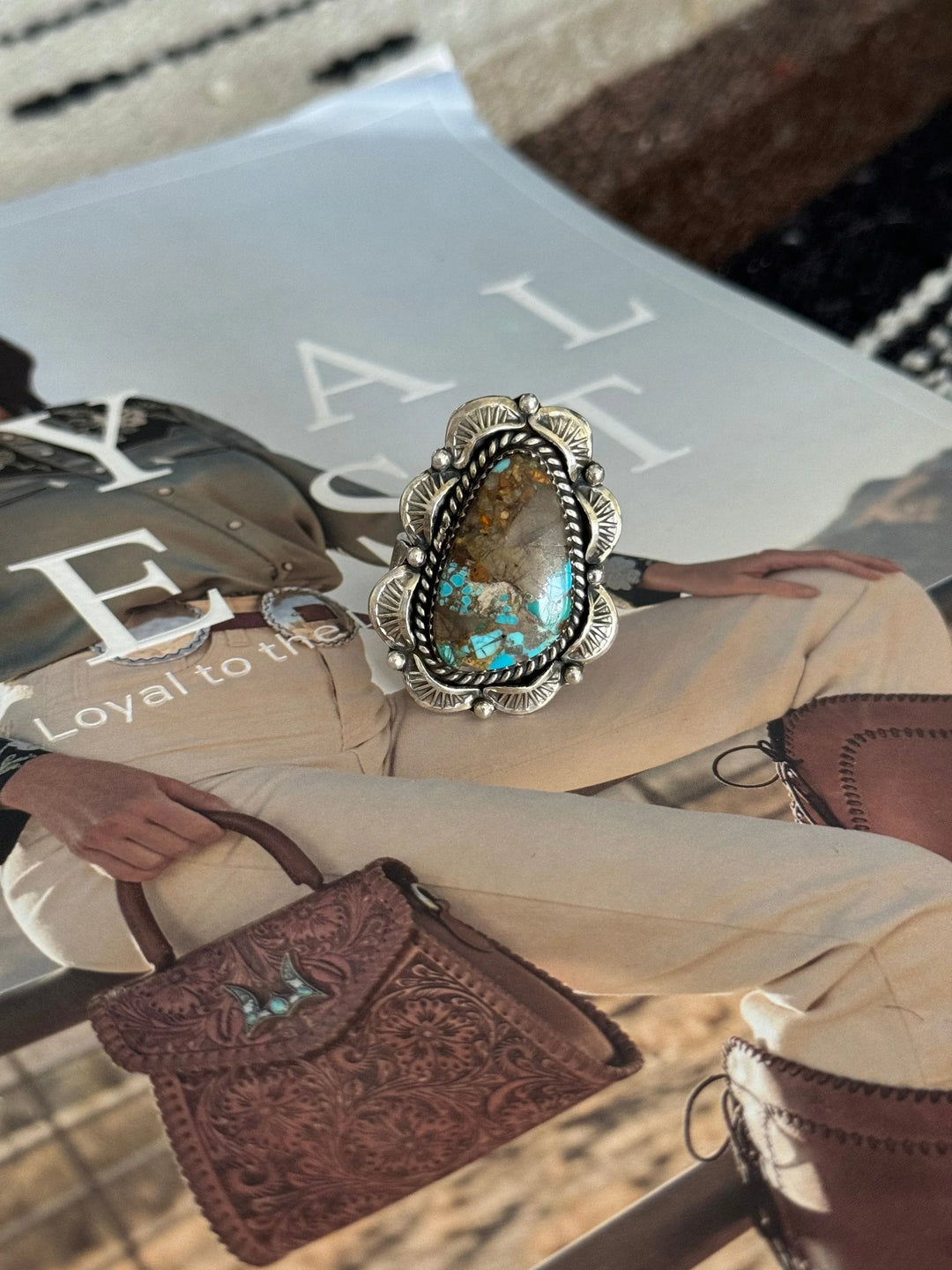 Western boho turquoise statement ring with engraved silver setting on magazine background