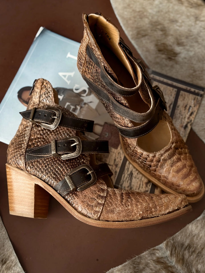 Brown snakeskin-patterned boots with wooden heel on a textured surface