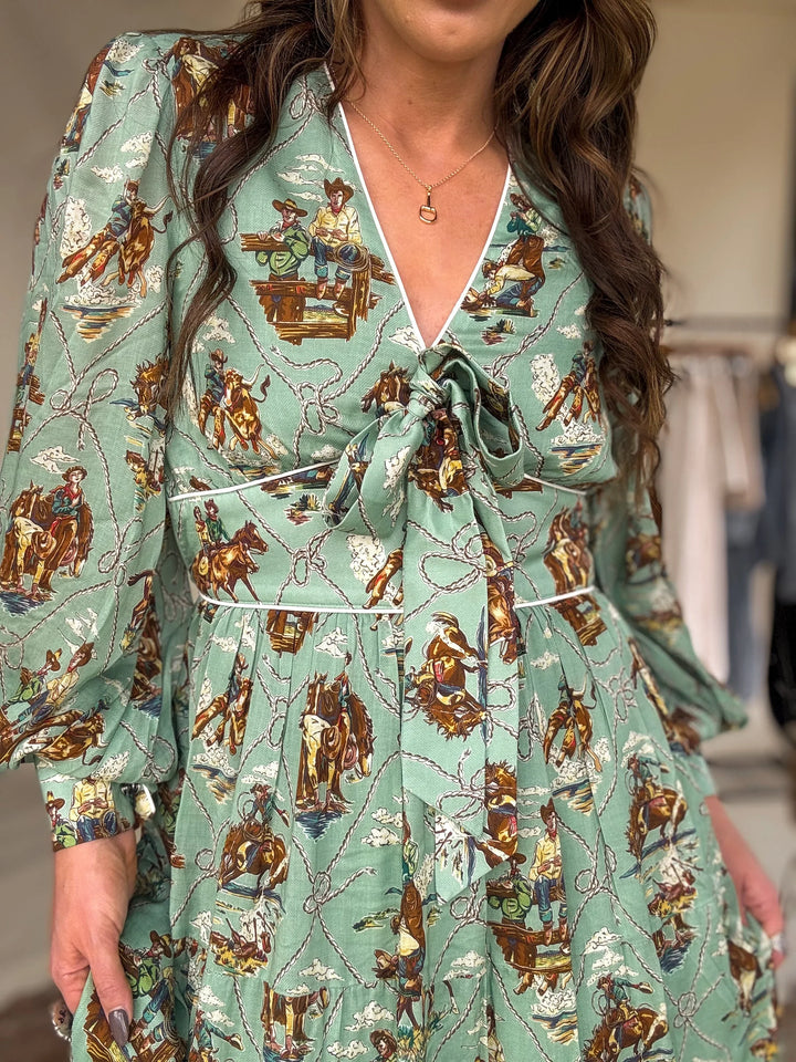 Woman wearing a western boho dress with cowgirl and rodeo print, long puff sleeves, and front tie.