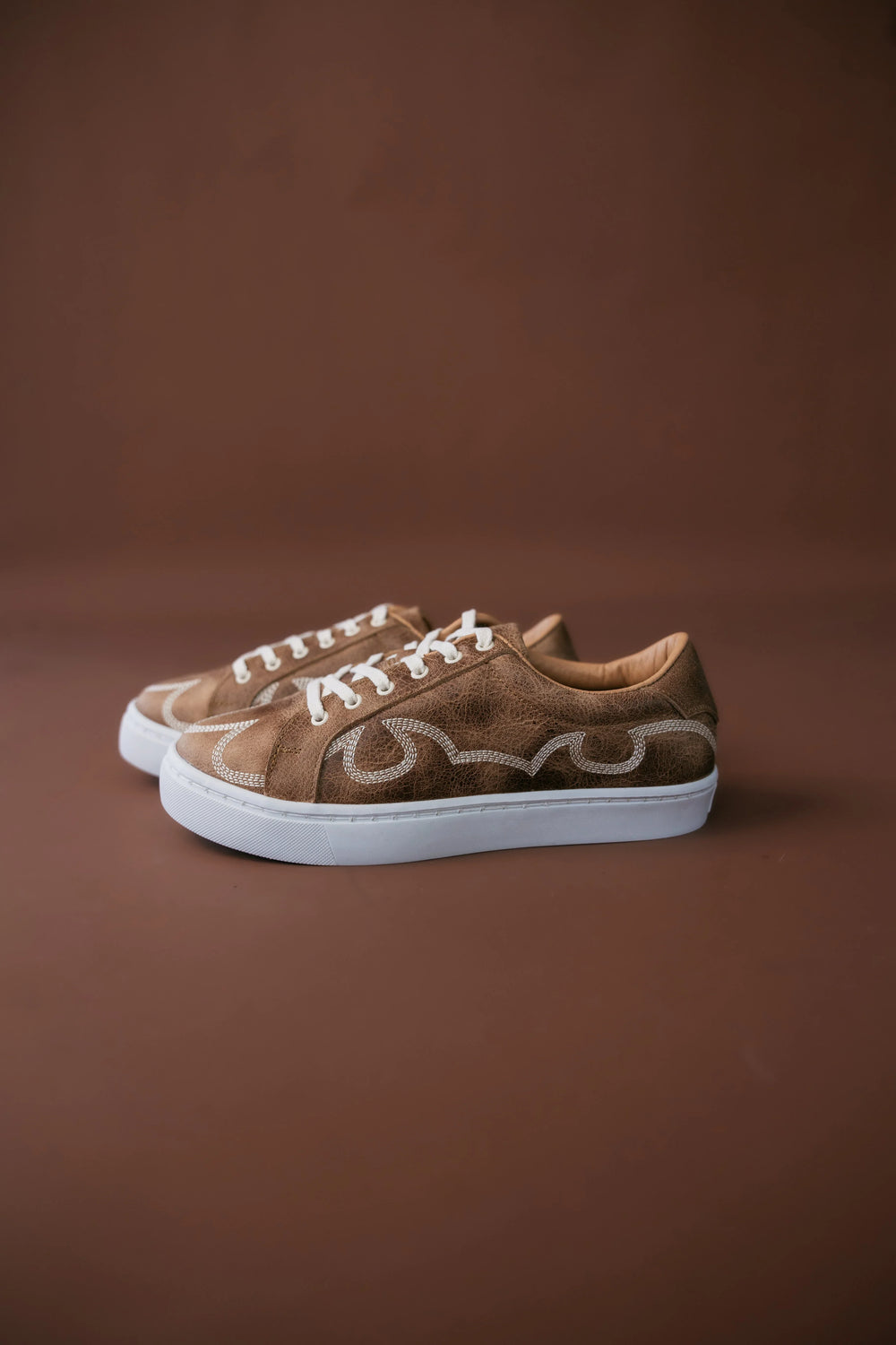Brown sneakers with white soles on a brown background