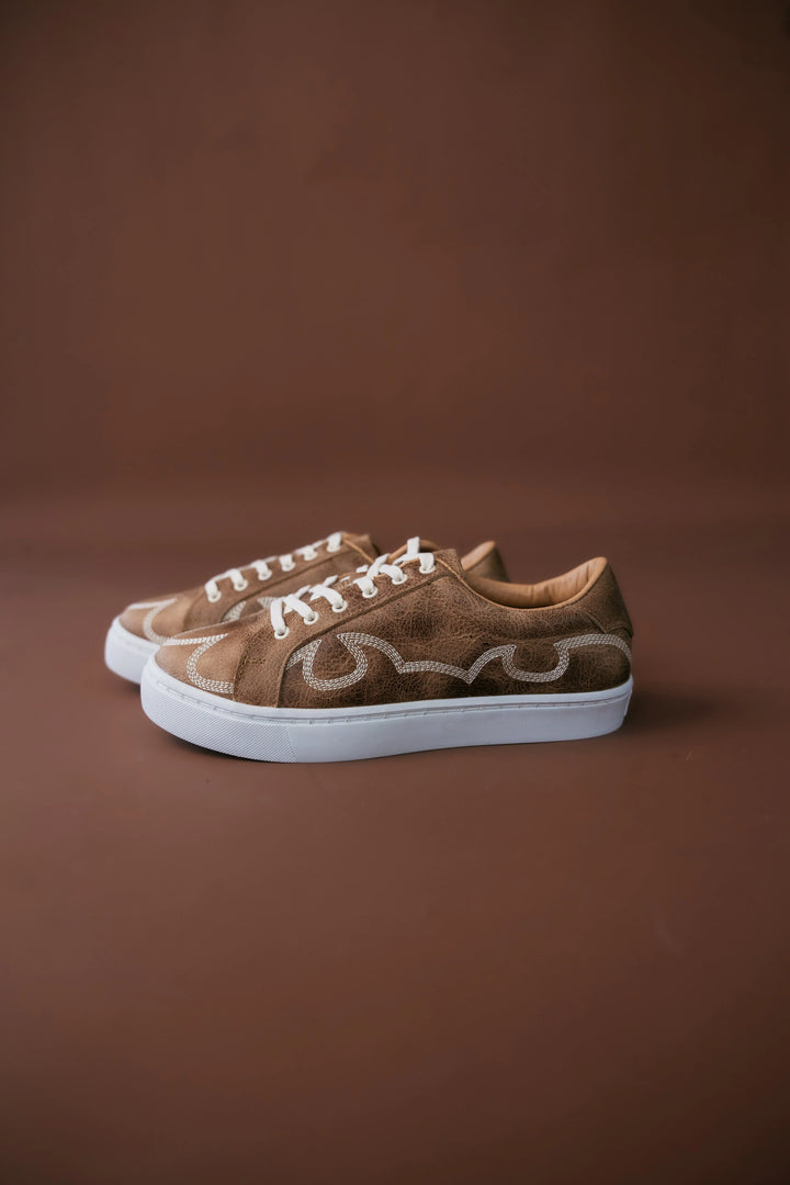 Brown sneakers with white soles on a brown background