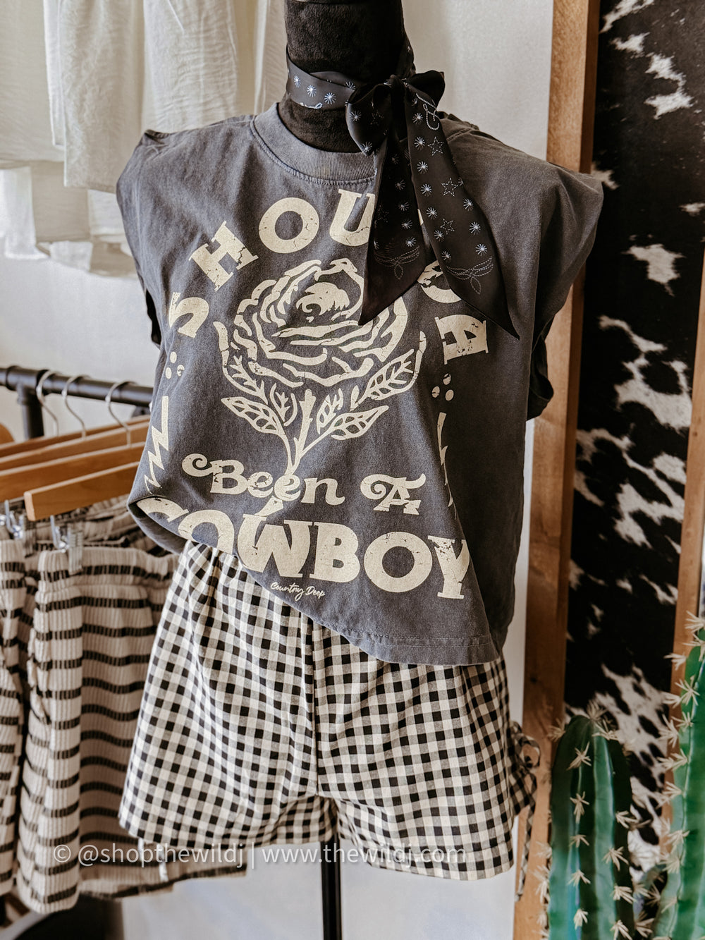 Mannequin wearing a graphic t-shirt with text and a rose design, paired with checkered shorts in a store setting.