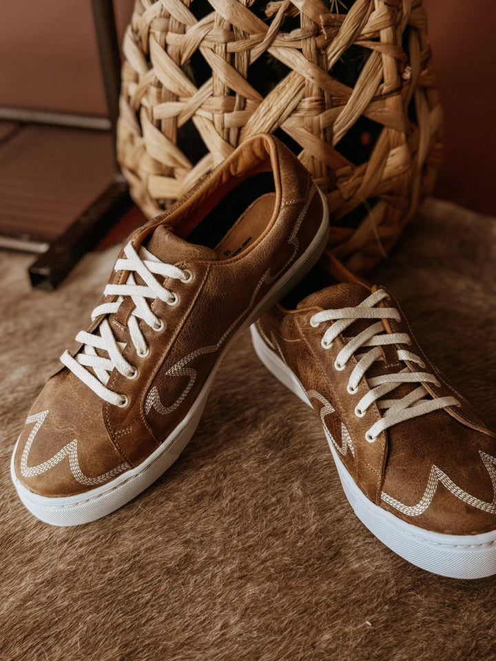 Brown sneakers with white laces on a textured surface