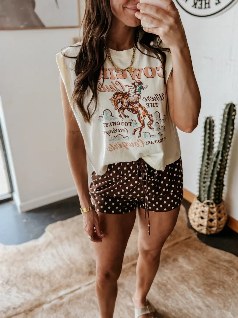 Woman wearing a graphic t-shirt and polka dot shorts in a casual setting.
