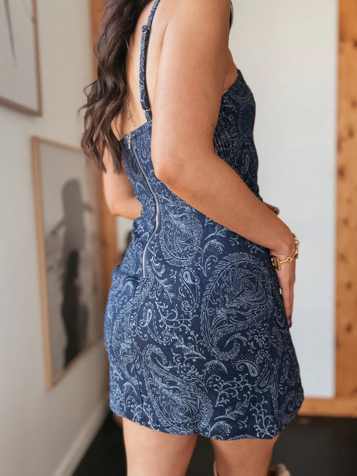 Woman wearing a blue paisley print western mini dress with adjustable straps indoors