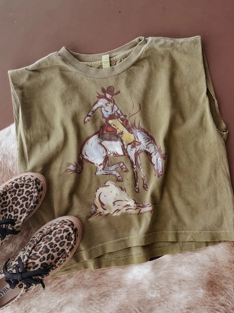 Green tank top with cowboy graphic on a brown surface with leopard print shoes.