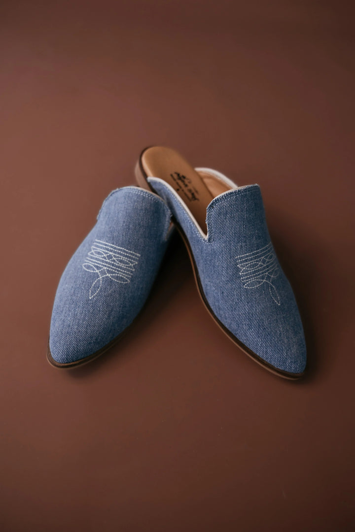 Pair of blue loafers with white embroidery on a brown background