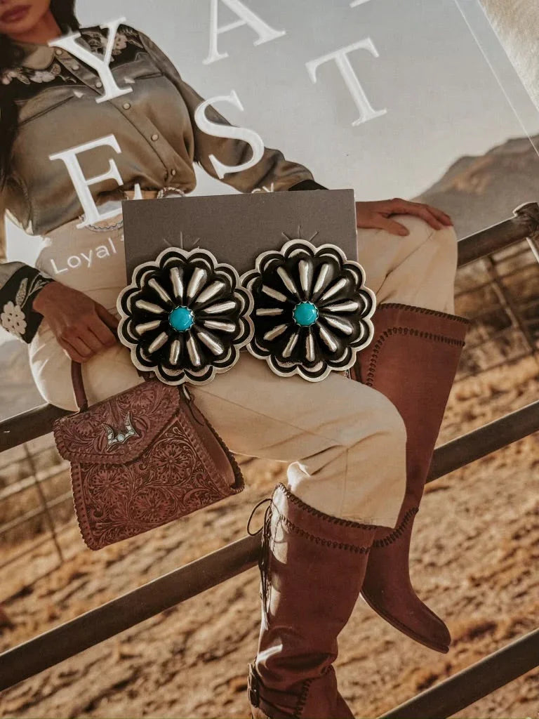 Western concho earrings with turquoise center on rodeo cowgirl magazine background
