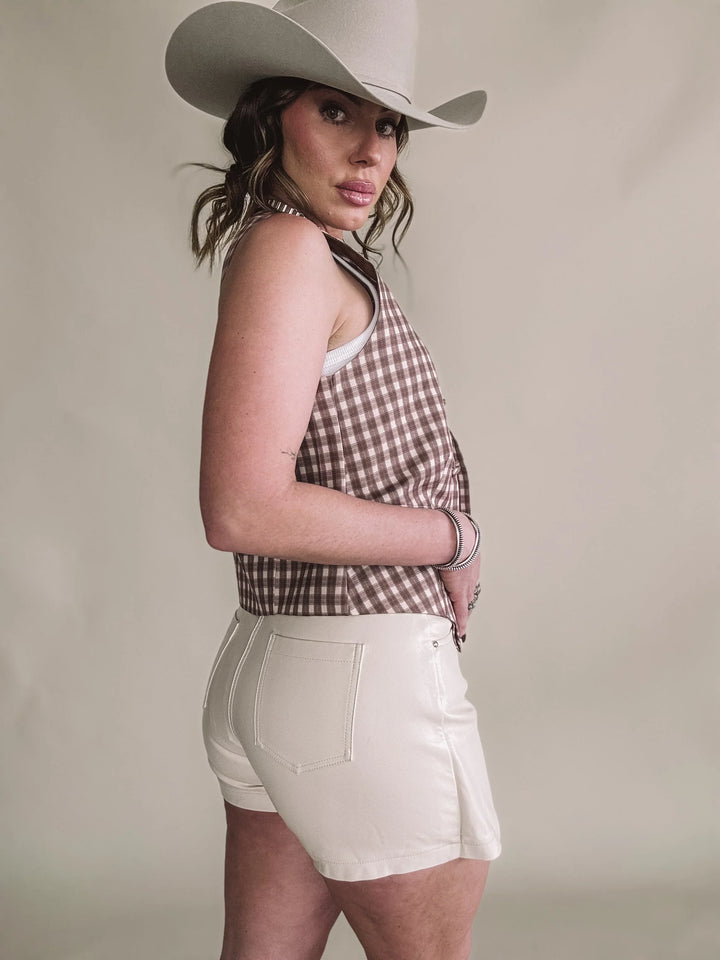 Woman in cowboy hat, gingham halter top, and white shorts, western boho fashion