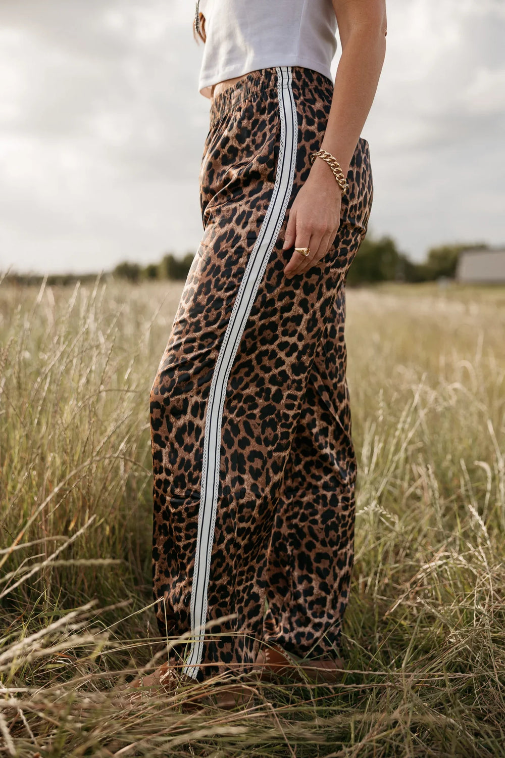 Person wearing a leopard print skirt with white stripes in a grassy field