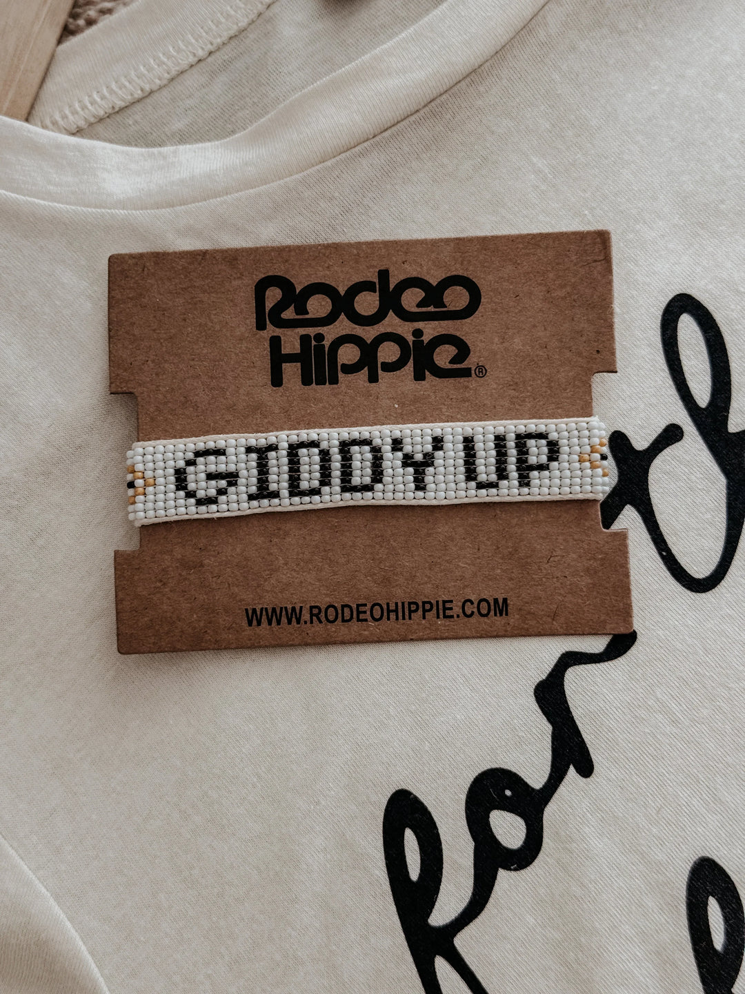 Bracelet with 'Giddy Up' text on a Rodeo Hippie branded card against a beige background.