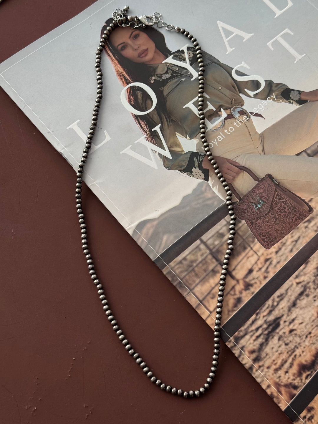 Necklace on a magazine with a fashion model and handbag