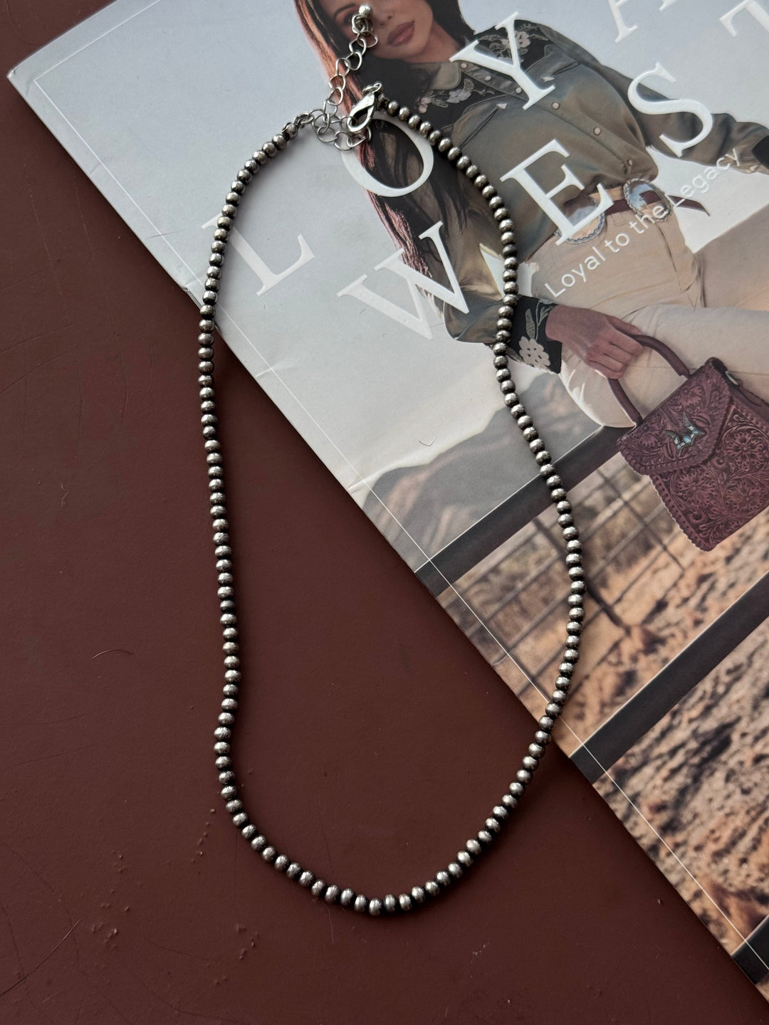 Silver beaded western necklace on magazine with cowgirl fashion background