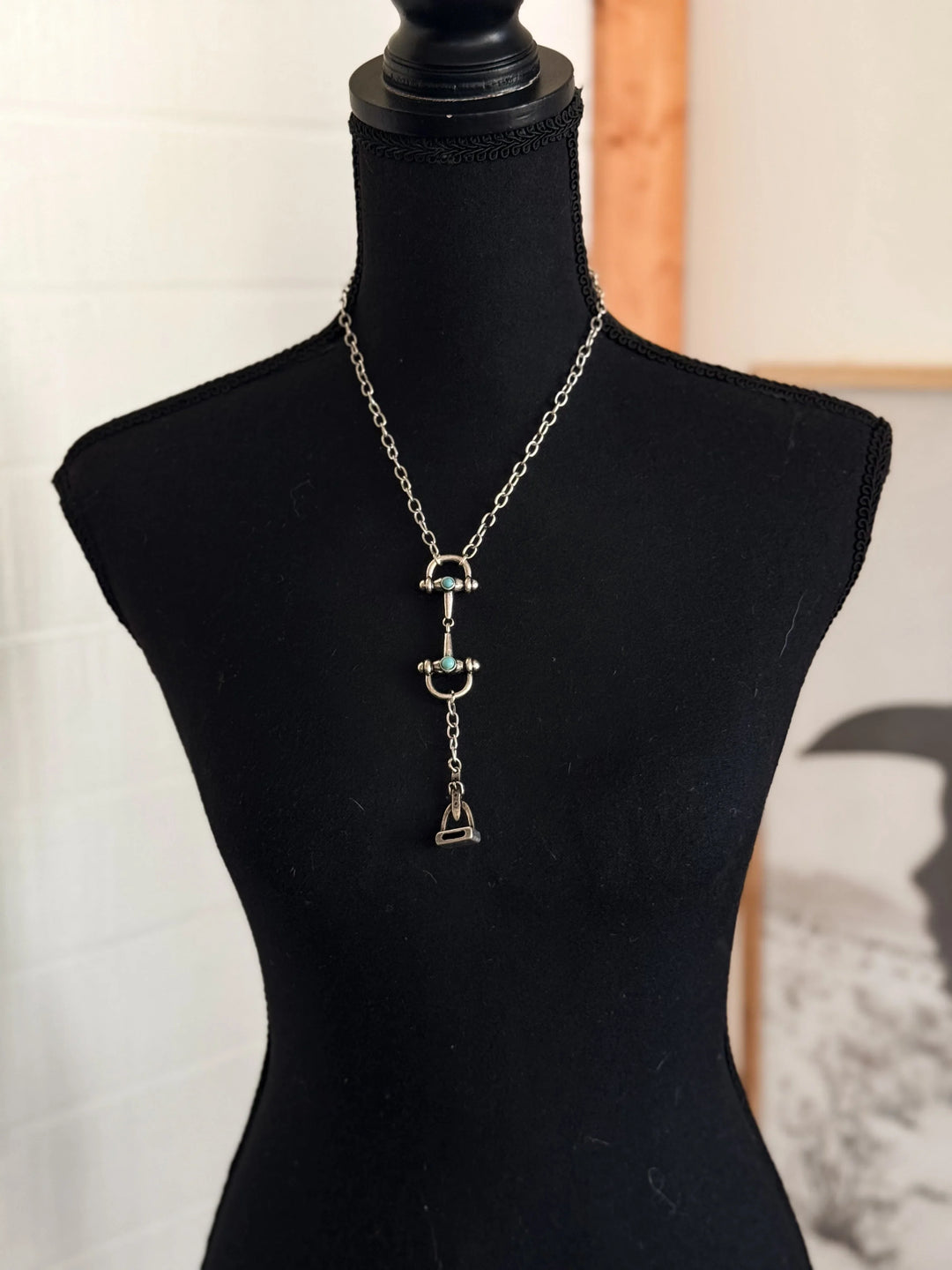 Necklace with a pendant on a black mannequin bust against a neutral background
