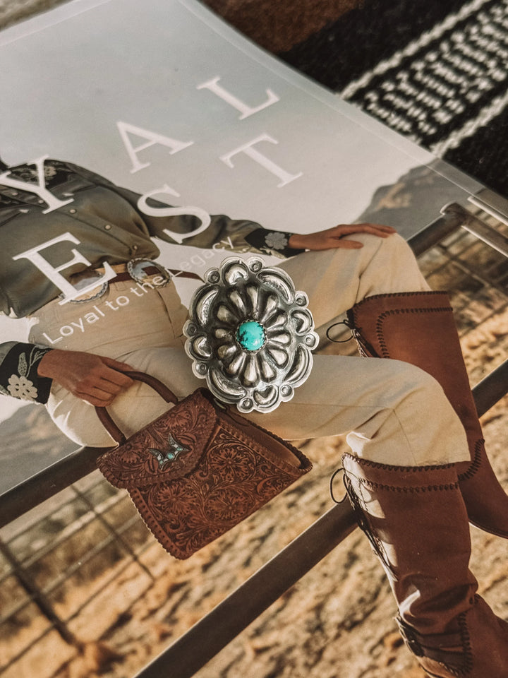 Silver Navajo concho ring with turquoise stone on western fashion magazine background