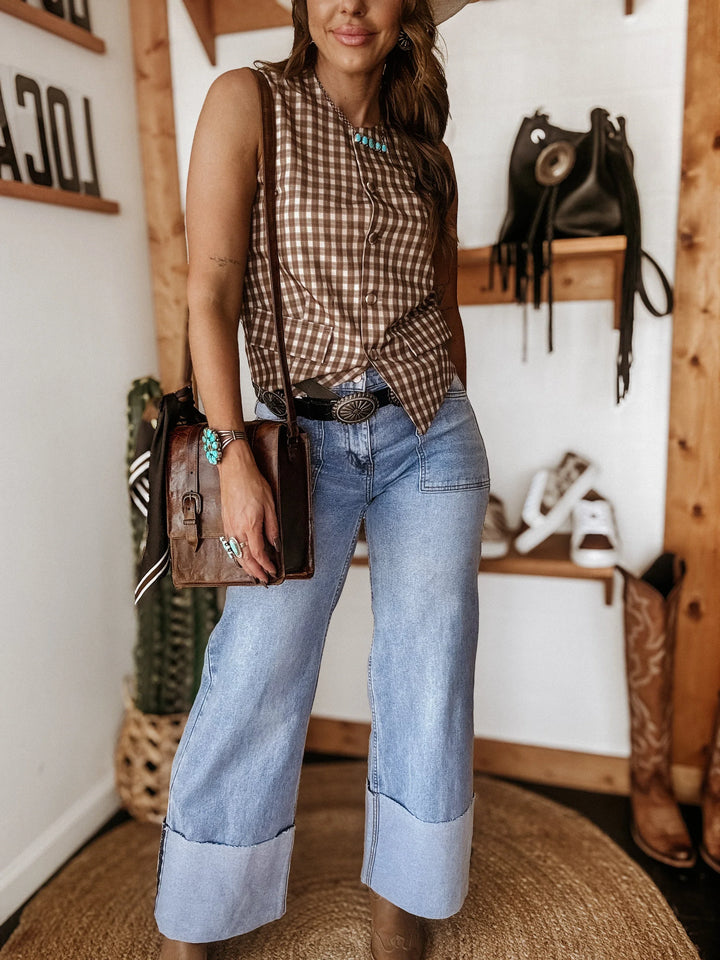 Woman in western wide leg jeans, sleeveless plaid top, turquoise jewelry, and cowgirl accessories